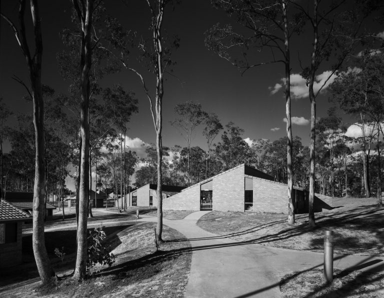 A black and white photograph showing villas constructed with brick, surrounded by trees